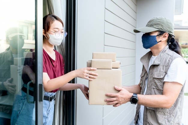 Woman receiving package from the delivery man, which she ordered products online